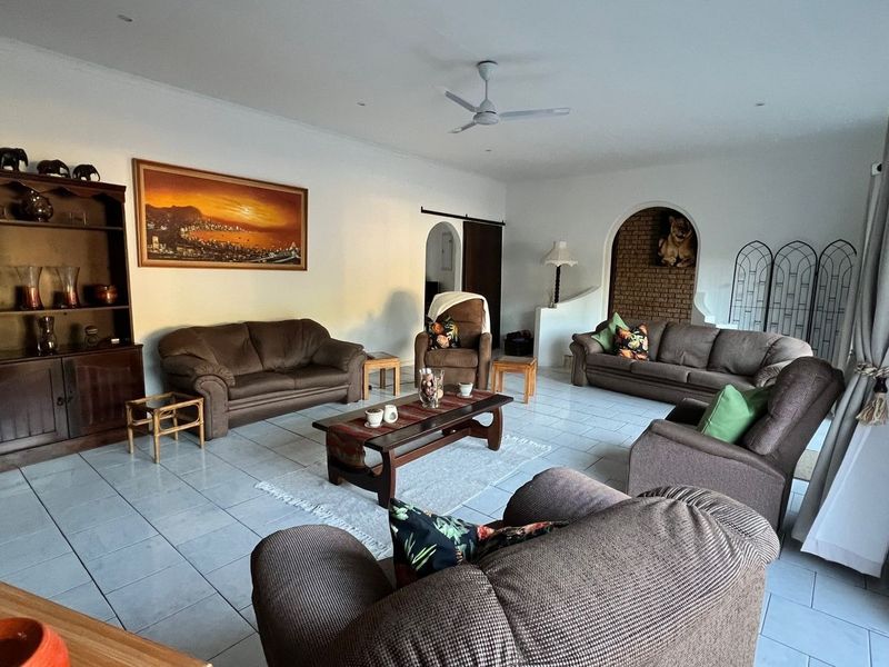 Spacious living room featuring tiled flooring, a ceiling fan, recessed lighting, and a decorative arched brick niche.