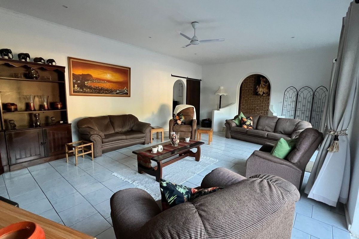 Spacious living room featuring tiled flooring, a ceiling fan, recessed lighting, and a decorative arched brick niche.