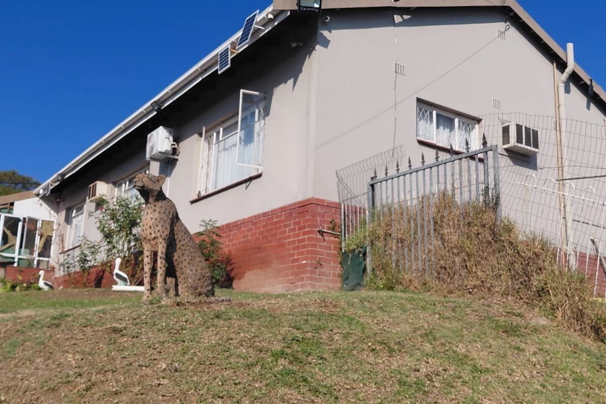 Rear view of the house featuring a brick base, security fencing, and installed solar panels on the roof.