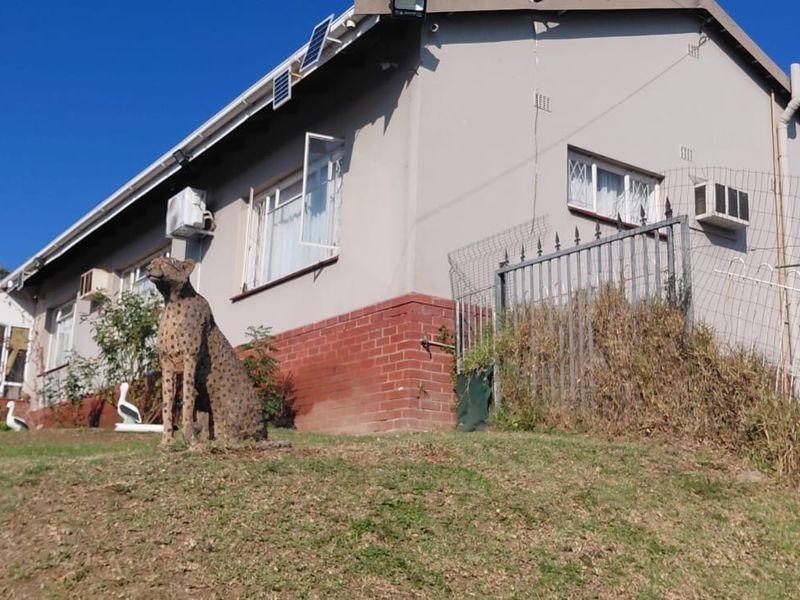 Rear view of the house featuring a brick base, security fencing, and installed solar panels on the roof.