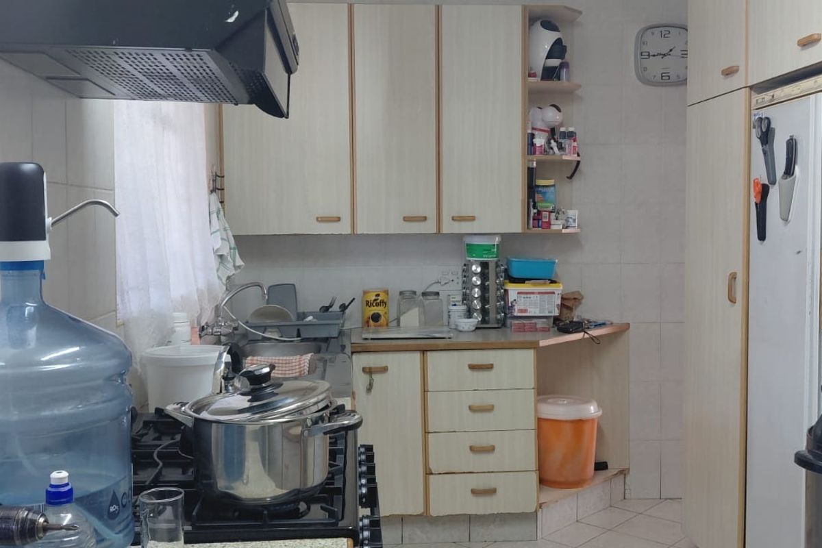 A functional kitchen featuring built-in cabinetry, a gas hob with extractor fan, and tiled splashbacks, offering a practical layout for daily meal preparation.