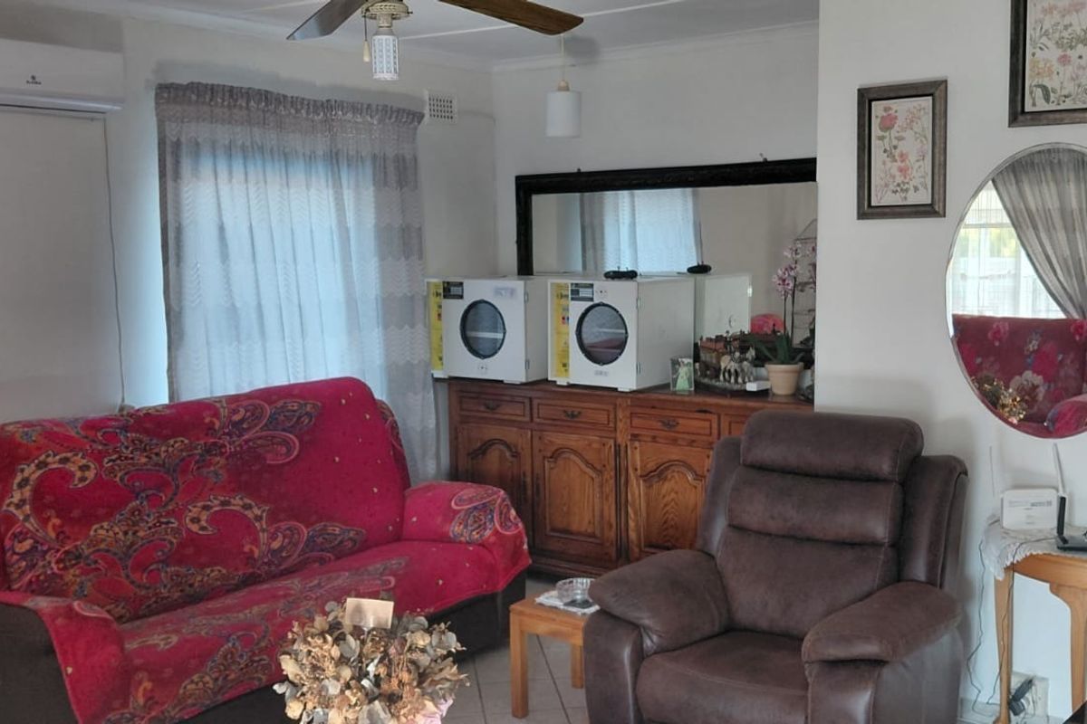 A living room featuring tiled flooring, a ceiling fan, and a wall-mounted split-system air conditioner.