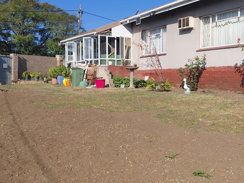 Rear exterior view of the house featuring a garden area, enclosed patio, and brick boundary wall.