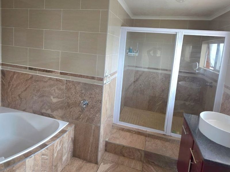 Modern bathroom featuring a built-in bathtub, a separate walk-in shower with glass enclosure, and a vessel sink vanity with tiled finishes.