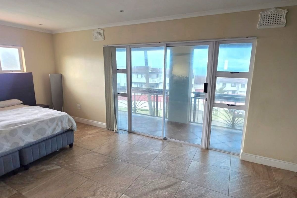 Spacious bedroom featuring tiled flooring and large sliding glass doors that provide access to a private balcony.