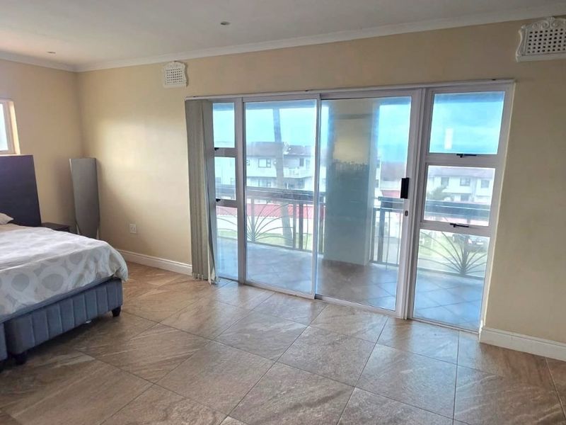 Spacious bedroom featuring tiled flooring and large sliding glass doors that provide access to a private balcony.