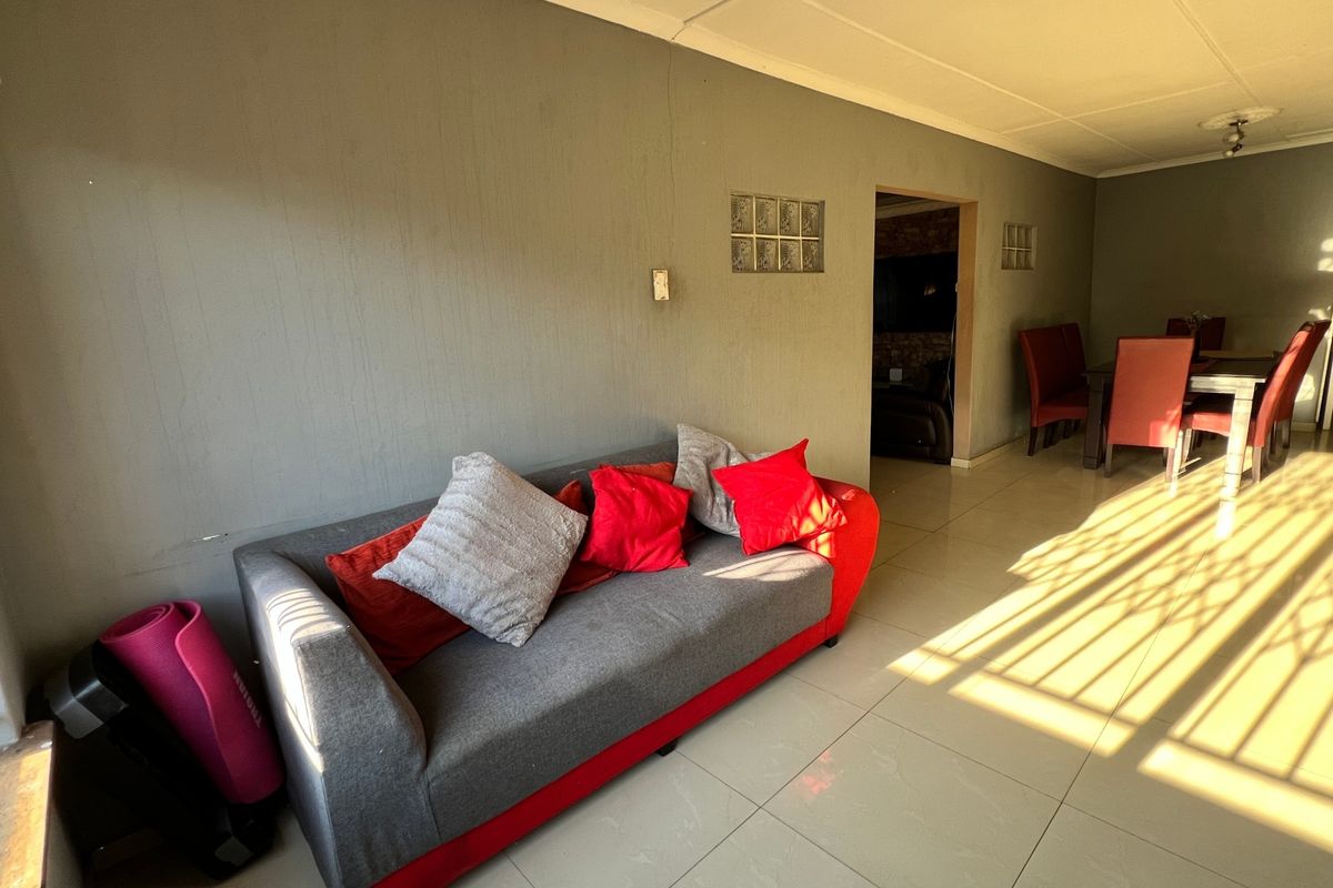 A living area featuring tiled flooring and a unique glass block wall insert, providing a functional space with potential for cosmetic updates.