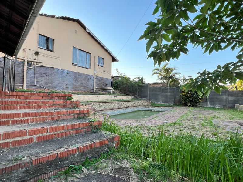 Rear exterior view featuring a swimming pool, tiered brick staircase, and retaining walls, requiring maintenance and landscaping to restore the outdoor space.