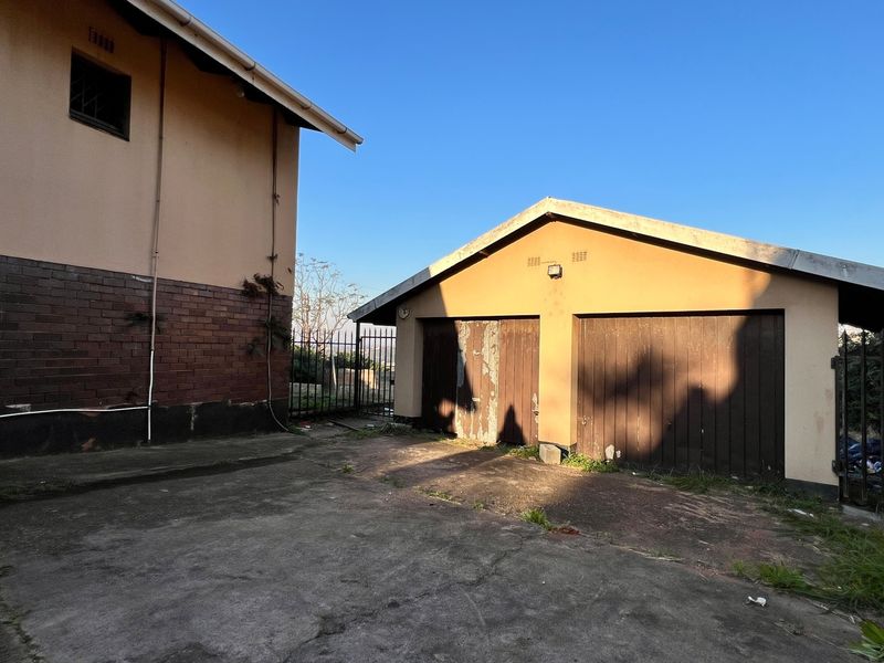 Exterior view of a detached double garage with weathered doors and a concrete driveway area.