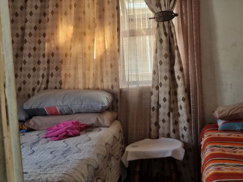 A bedroom interior featuring a window with curtains, showing basic finishes and a compact layout.