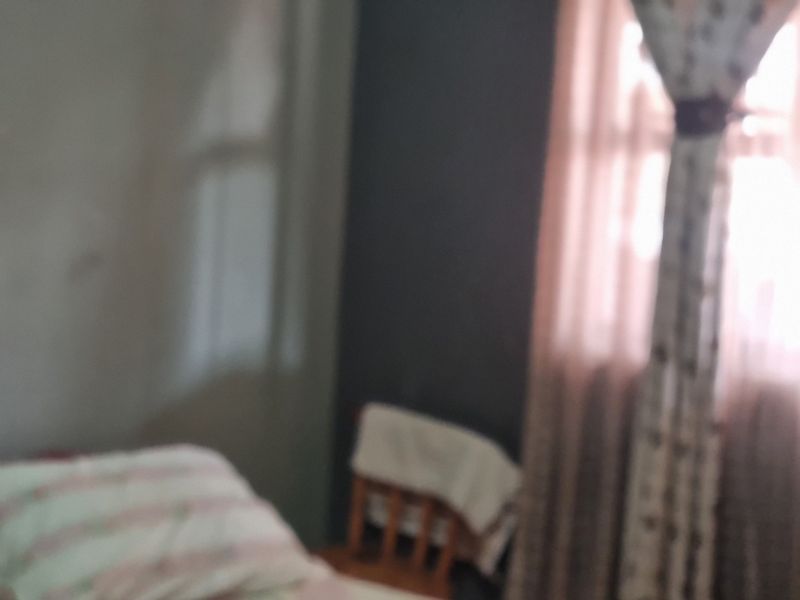 A blurry interior view of a bedroom featuring a window with curtains.