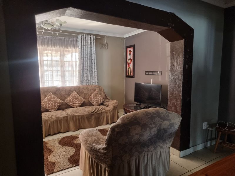 A cozy living room featuring a distinct architectural archway, tiled flooring, and natural light through the window.