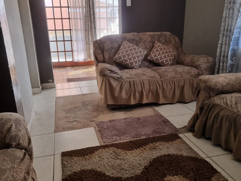 Living room area featuring tiled flooring and a glass paneled door providing access to the exterior.