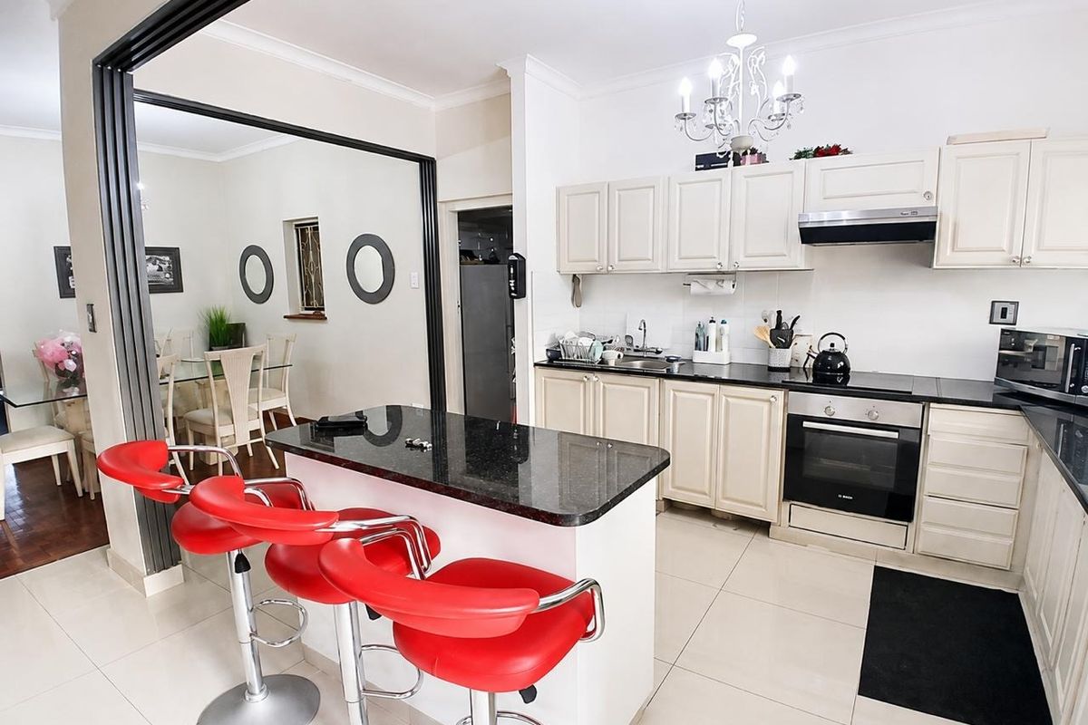 Open-plan kitchen featuring granite countertops, built-in oven, electric hob, and extractor fan, seamlessly flowing into the adjacent dining area.