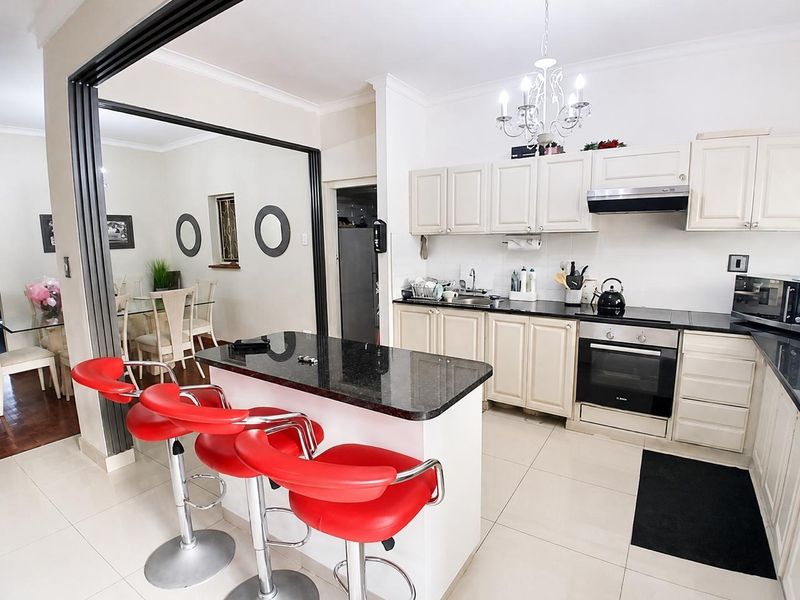 Open-plan kitchen featuring granite countertops, built-in oven, electric hob, and extractor fan, seamlessly flowing into the adjacent dining area.