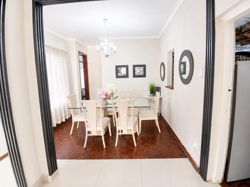 A well-maintained dining room featuring classic parquet flooring, a decorative chandelier, and coved ceilings, providing a bright and inviting space for meals.