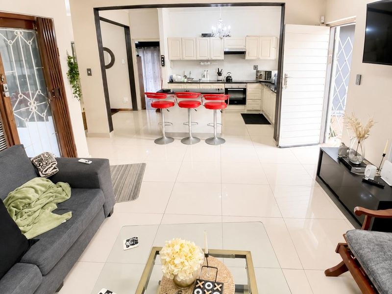 Open-plan living area featuring polished tiled floors and a functional kitchen with built-in cabinetry, island seating, and integrated appliances.