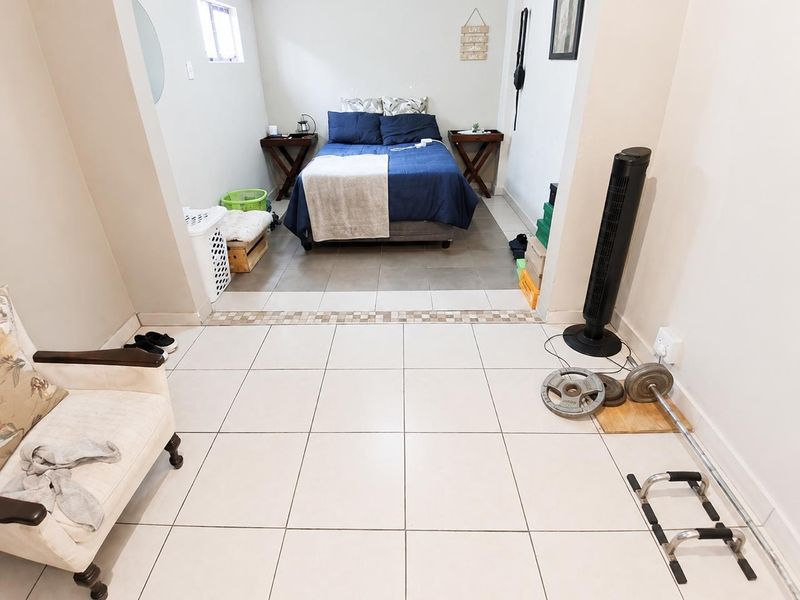 A bedroom featuring tiled flooring with a decorative mosaic border, providing a functional space with neutral wall finishes.
