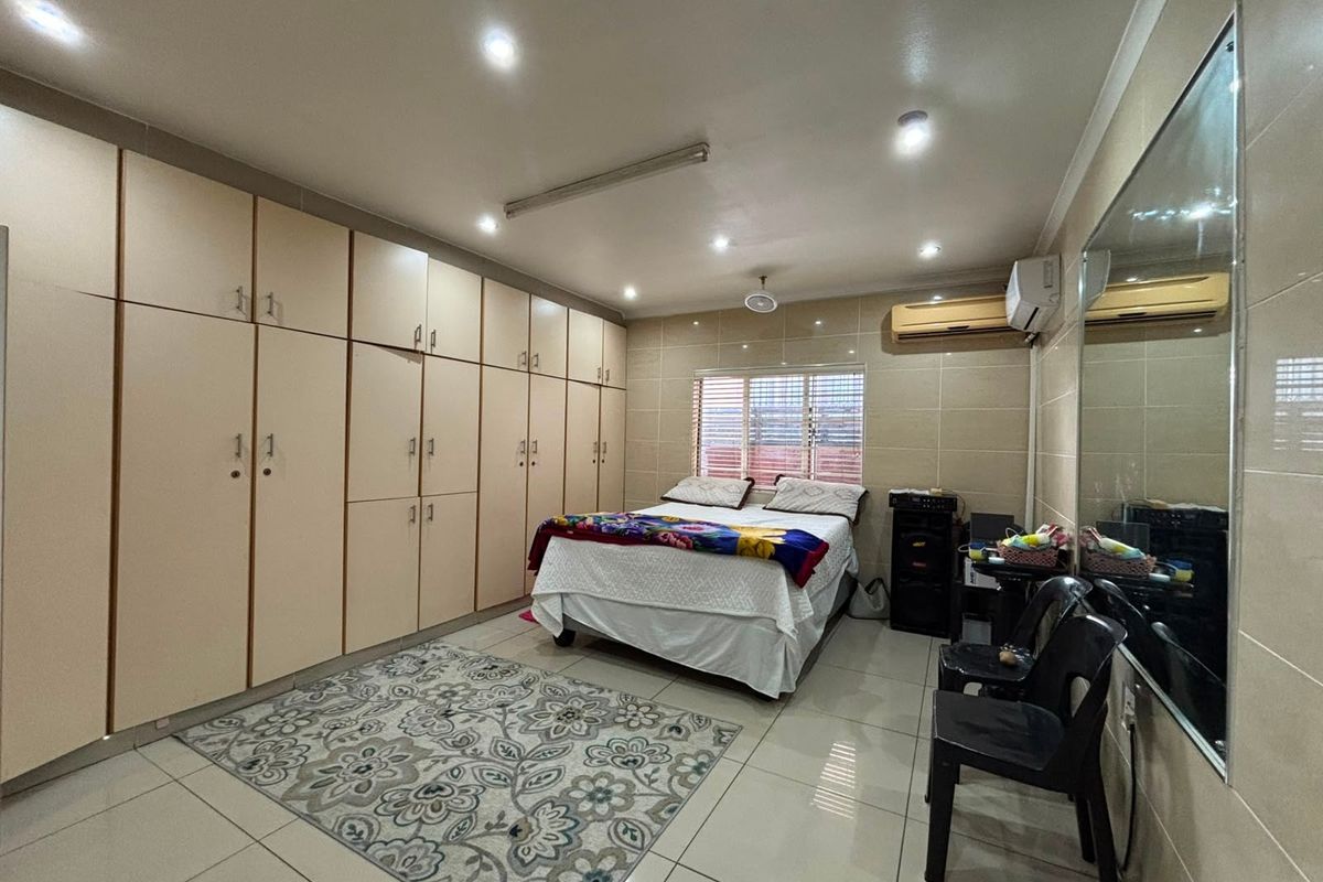 Spacious bedroom featuring extensive built-in cabinetry, tiled flooring throughout, recessed lighting, and a wall-mounted air conditioning unit.