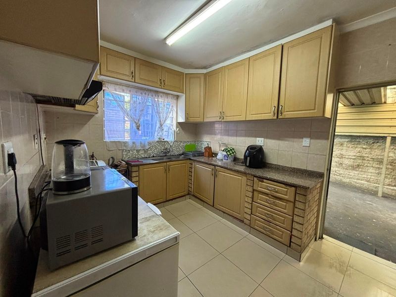 A dated kitchen featuring laminate cabinetry, granite countertops, and tiled flooring, offering a functional layout with potential for modern renovation.