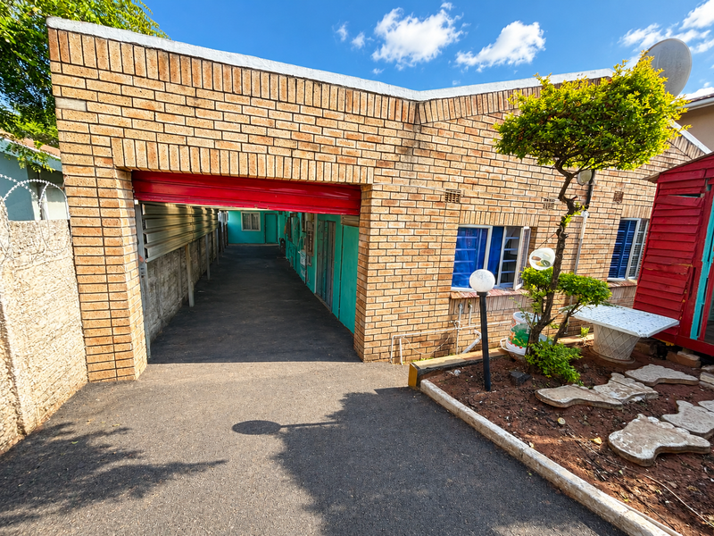 Front exterior view of the property featuring a face brick facade, a roller shutter garage entrance, and a paved driveway area.