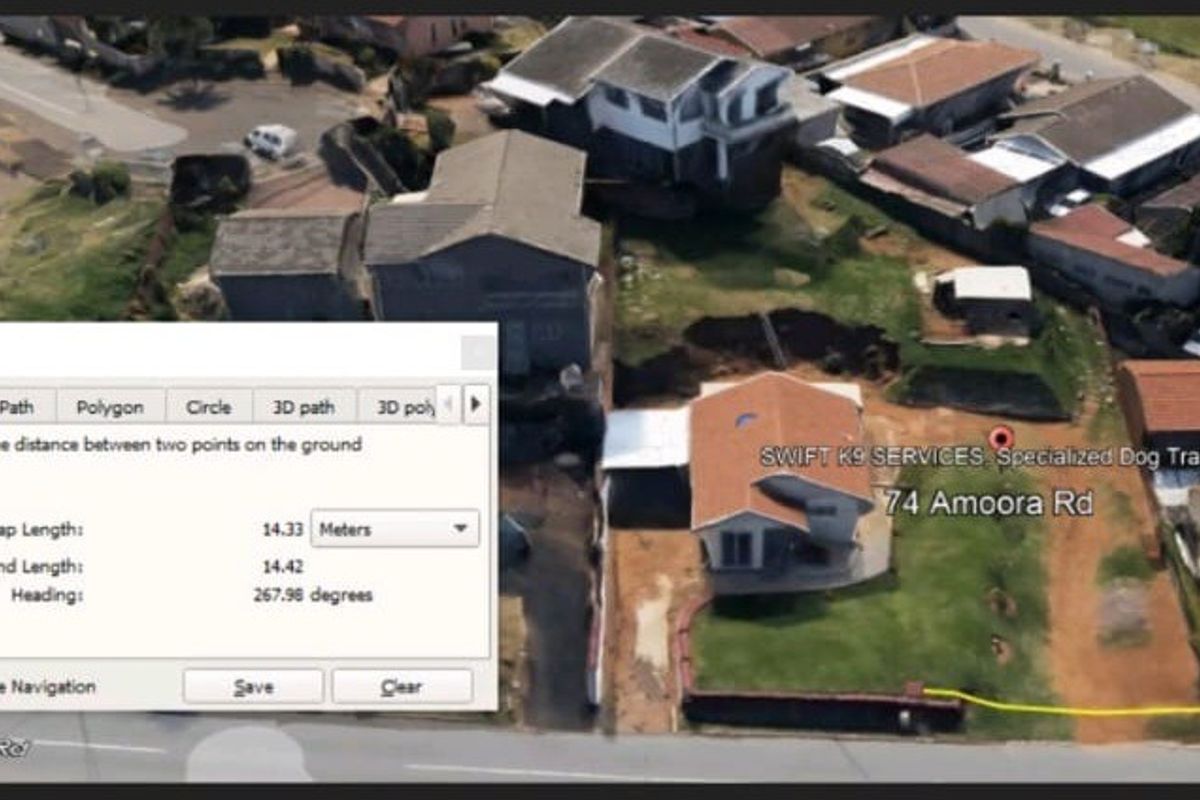 Aerial view of a residential property showing the dwelling, driveway, and surrounding land layout.