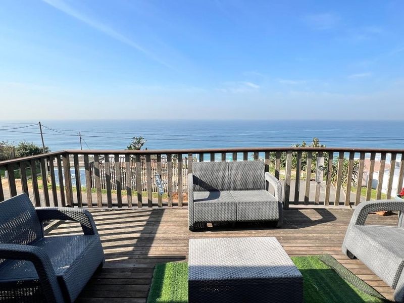 An elevated timber deck balcony featuring a wooden balustrade and expansive, unobstructed ocean views.