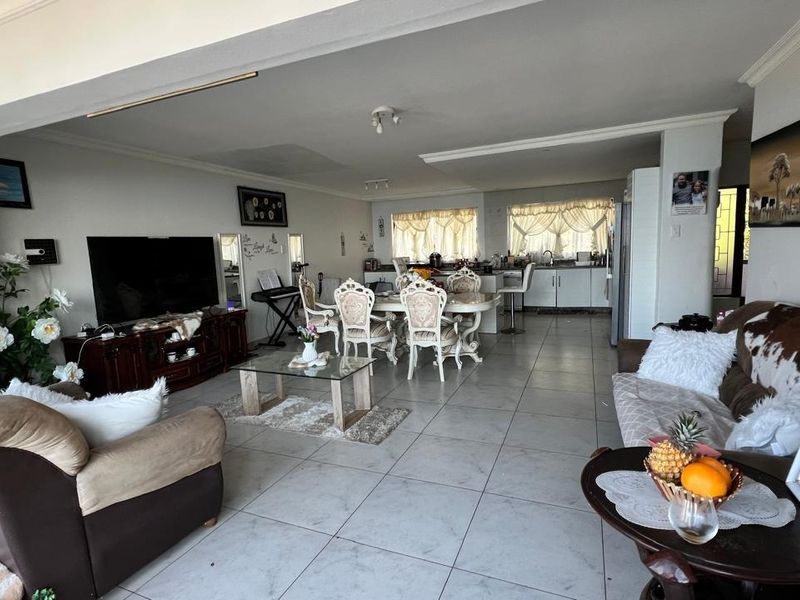 Spacious open-plan living and dining area featuring tiled flooring, integrated kitchen cabinetry, and a functional layout suitable for modern family living.