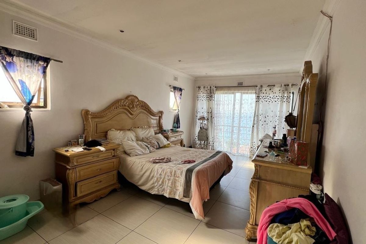 Spacious bedroom featuring tiled flooring, cornicing, and a sliding glass door providing access to the exterior.
