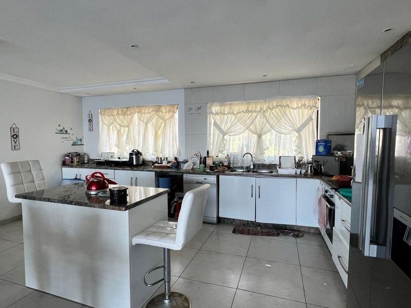 A functional kitchen featuring a central island with granite countertops, white cabinetry, tiled flooring, and integrated appliances.