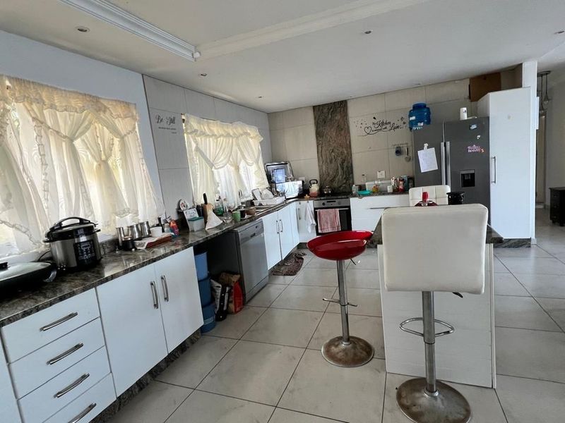 Spacious kitchen featuring white cabinetry, granite countertops, a central island, and tiled flooring, offering a functional layout for cooking and casual dining.