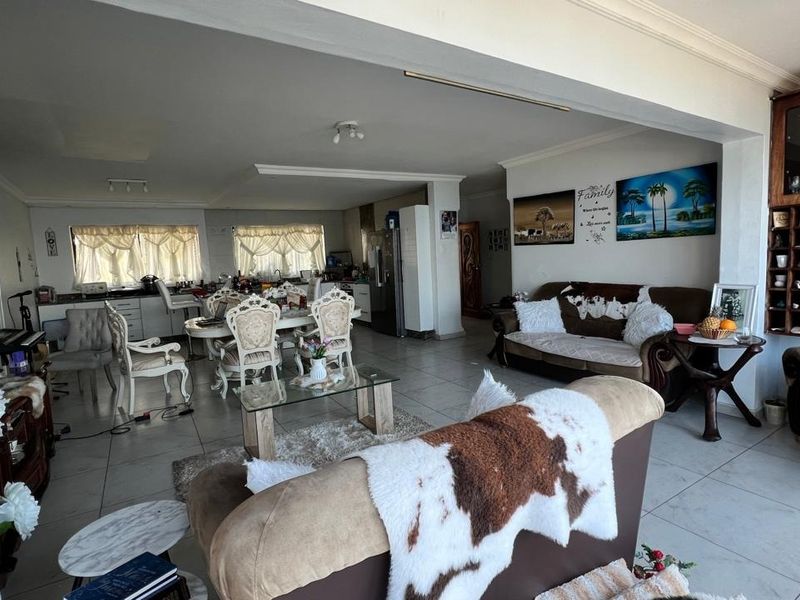 Spacious open-plan living and dining area featuring tiled flooring and an integrated kitchen space, offering a versatile layout for family living.