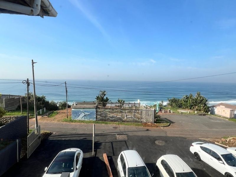 Elevated view overlooking the coastal area, featuring a paved driveway and direct ocean outlook.