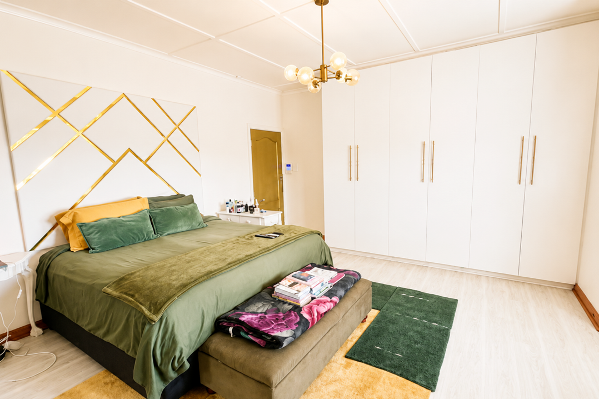 Spacious bedroom featuring extensive built-in wardrobes, modern laminate flooring, and a decorative ceiling design with a contemporary pendant light fixture.
