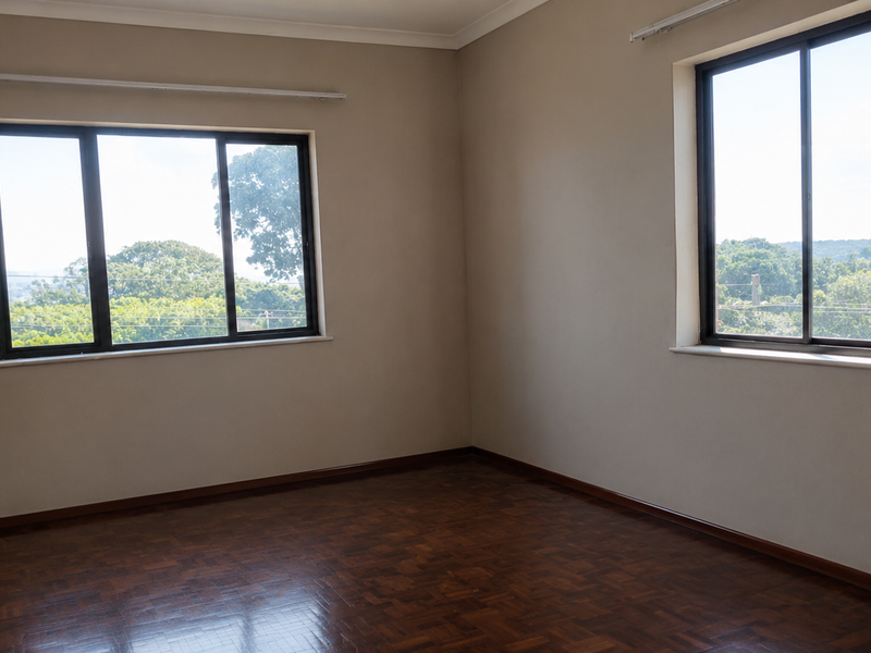 A bright, empty bedroom featuring polished parquet flooring, neutral walls, and large aluminium-framed windows offering pleasant natural light and views.