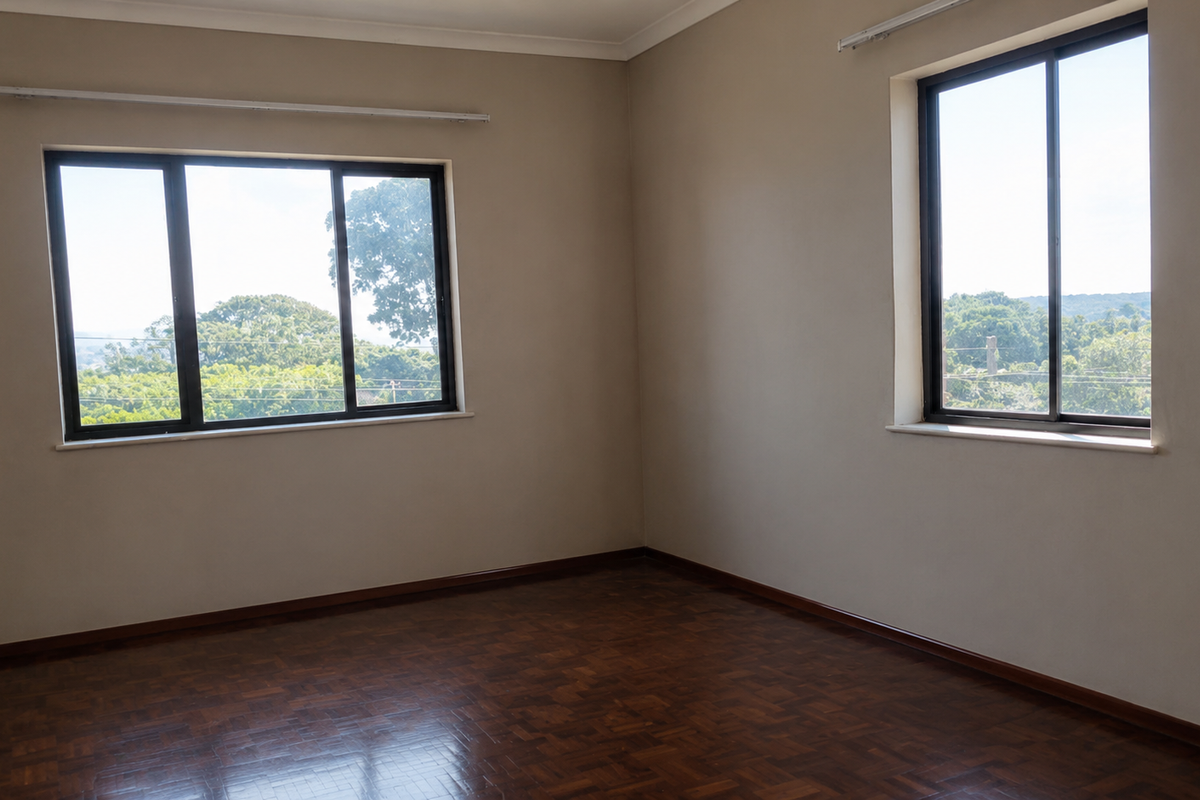 A bright, empty bedroom featuring polished parquet flooring, neutral walls, and large aluminium-framed windows offering pleasant natural light and views.