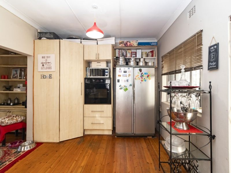 A functional kitchen area featuring built-in cabinetry, an integrated oven and microwave, and warm timber flooring with natural light from the window.