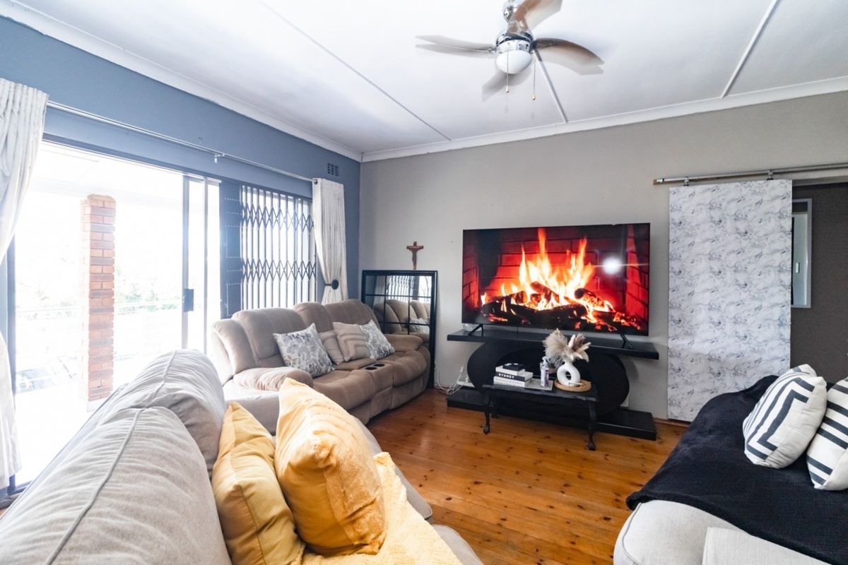 A comfortable living room featuring polished hardwood flooring, a ceiling fan, and large sliding glass doors that provide access to the outdoor area.