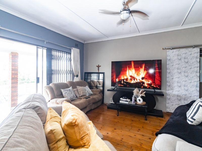 A comfortable living room featuring polished hardwood flooring, a ceiling fan, and large sliding glass doors that provide access to the outdoor area.
