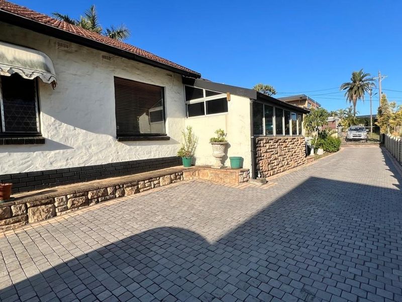 A view of the property's exterior featuring a paved driveway, stone-clad accents, and a tiled roof facade.