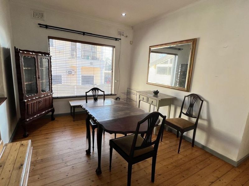 A dining room featuring original timber flooring, neutral walls, and natural light through venetian blinds, offering a classic foundation for modern updates.
