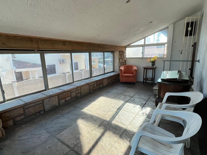 Enclosed patio area featuring stone-clad window sills, exposed timber beams, and large windows providing ample natural light.