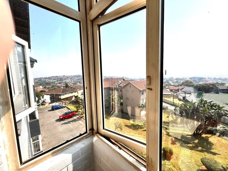 A view from an elevated apartment window overlooking the surrounding residential neighbourhood and parking area.