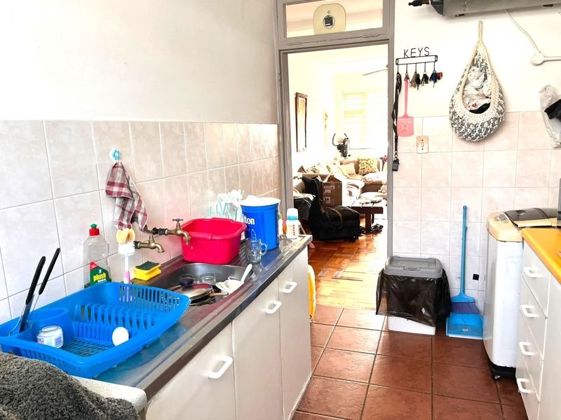 A functional kitchen area featuring a stainless steel sink, tiled backsplash, and built-in cabinetry, with direct access to the adjacent living space.