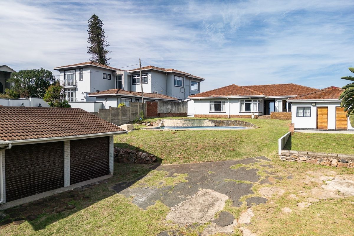Rear view of the property featuring a swimming pool, detached garage, and a large garden area with a paved driveway.