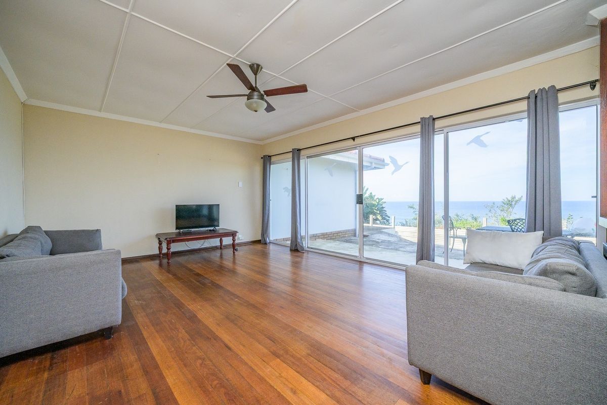 Spacious living room featuring polished hardwood floors, a ceiling fan, and large sliding glass doors that provide natural light and access to the outdoors.