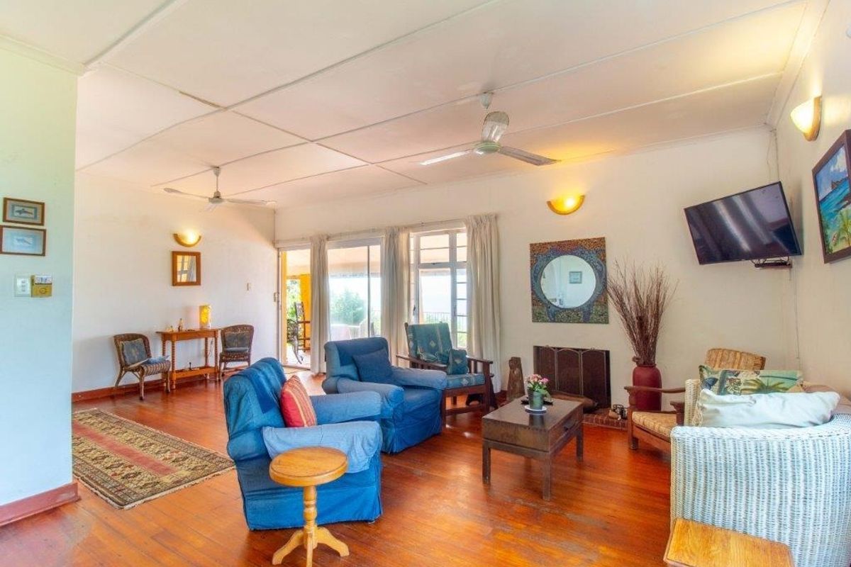 Spacious living room featuring hardwood flooring, ceiling fans, a fireplace, and sliding glass doors providing access to the outdoor area.