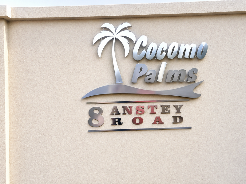 A clear view of the Cocomo Palms apartment complex signage mounted on the exterior building facade at 8 Anstey Road.