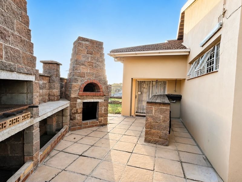 Outdoor patio area featuring a built-in brick braai and pizza oven, providing a functional space for outdoor entertaining and dining.