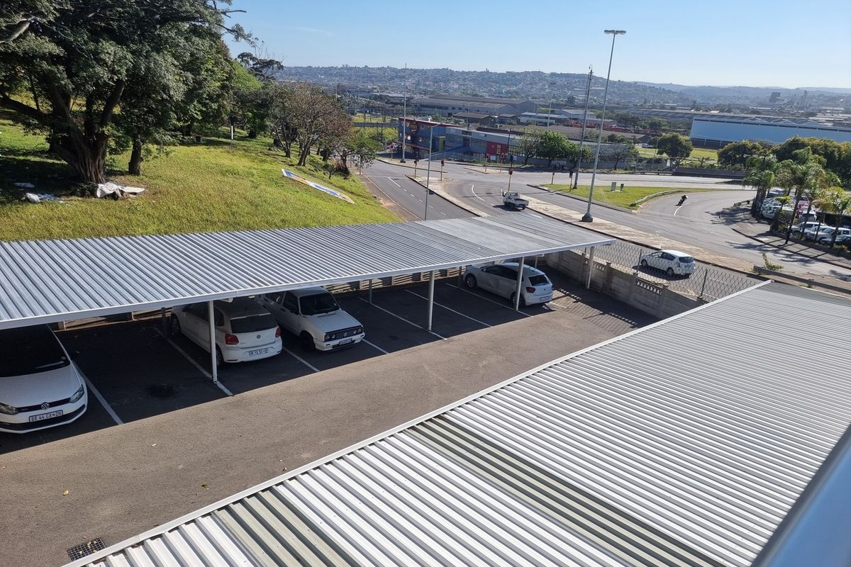 An elevated view of the apartment complex parking area featuring covered carports and paved parking bays.